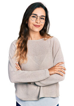Beautiful hispanic woman wearing casual sweater and glasses happy face smiling with crossed arms looking at the camera. positive person.