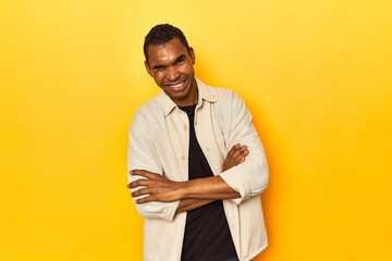 African American man with shirt, yellow studio, unhappy looking in camera with sarcastic expression.