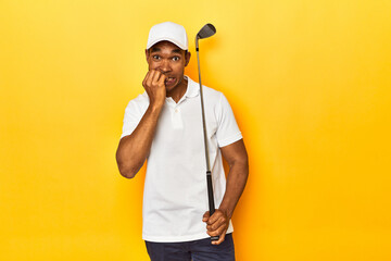 African American man golfer, yellow studio backdrop, biting fingernails, nervous and very anxious.
