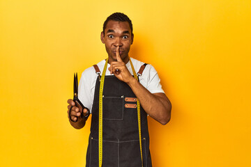 African American tailor with tools, yellow studio, keeping a secret or asking for silence. - obrazy, fototapety, plakaty