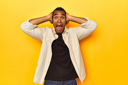African American man with shirt, yellow studio, screaming, very excited, passionate, satisfied with something.