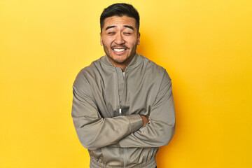 Stylish Asian man in gray jacket on yellow studio laughing and having fun.