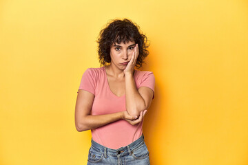 Curly-haired Caucasian woman in pink t-shirt who is bored, fatigued and need a relax day.