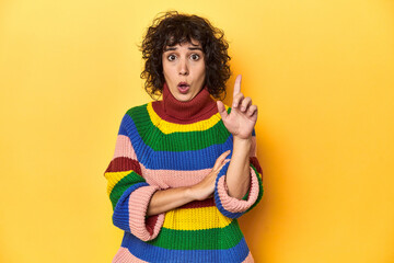 Curly-haired woman in multicolor sweatshirt having some great idea, concept of creativity.