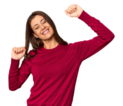 Elegant middle-aged Caucasian woman in studio setting celebrating a special day, jumps and raise arms with energy.