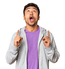 Athletic Chinese man in sportswear in studio pointing upside with opened mouth.