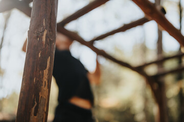 A fit young man in sportswear enjoys a day off hiking in the forest, doing pull ups on a tree. The...