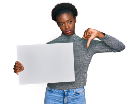 Young african american girl holding blank empty banner with angry face, negative sign showing dislike with thumbs down, rejection concept