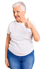 Senior beautiful woman with blue eyes and grey hair wearing casual white tshirt doing happy thumbs up gesture with hand. approving expression looking at the camera showing success.