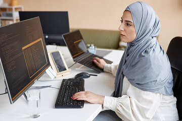 Side view portrait of Muslim young woman wearing modest clothing in office while working as female...