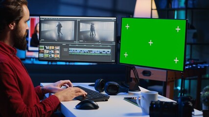 Video editor trimming segments of drone shot footage, using green screen PC monitor to work....