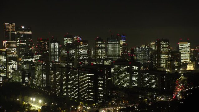 TOKYO, JAPAN - NOV 2023 : Close up shot of crowded office buildings at night. Japanese business, real estate, company, labour and work concept video. 4K time lapse shot.