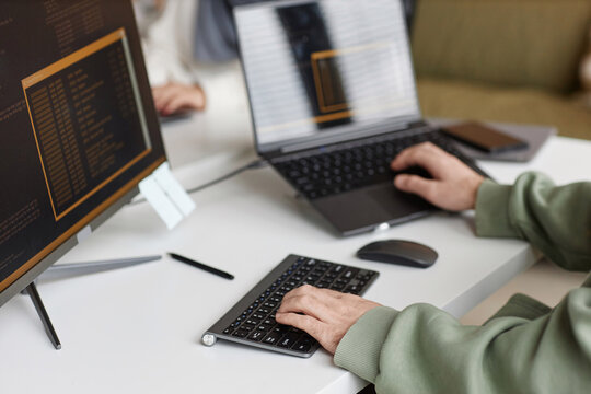 Closeup of male hands typing at computer keyboard with unrecognizable software programmer writing code, copy space