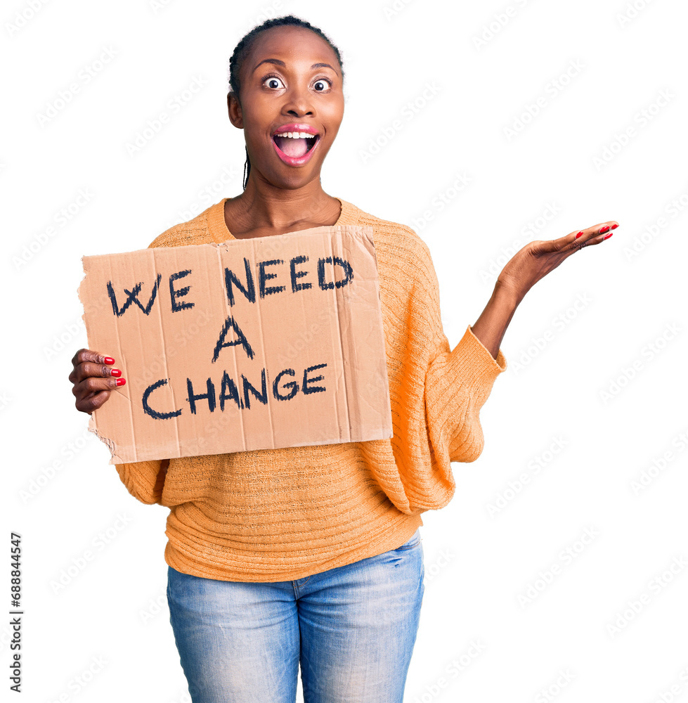 Sticker Young african american woman holding we need a change banner celebrating victory with happy smile and winner expression with raised hands