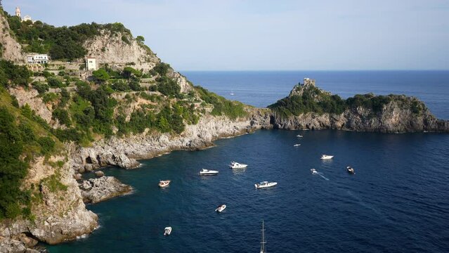 Idyllic view from mountain on yachts and boats docked near rocky headland with Torre del capo di Conca. Ship sailing in Mediterranean sea on background of beautiful seascape and mountain on summer day