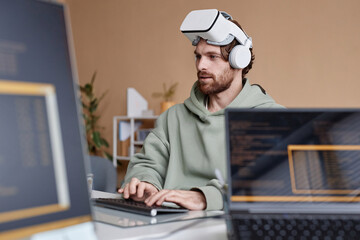 Side view portrait of bearded IT developer wearing VR headset working on immersive technology in...