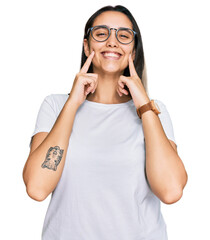 Young hispanic woman wearing casual white t shirt smiling with open mouth, fingers pointing and...