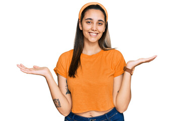 Young hispanic woman wearing casual clothes smiling showing both hands open palms, presenting and...