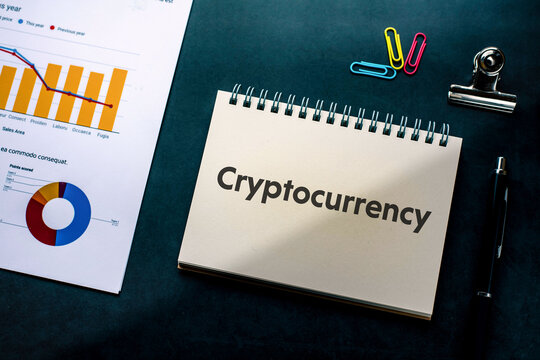 There is notebook with the word Cryptocurrency. It is as an eye-catching image.