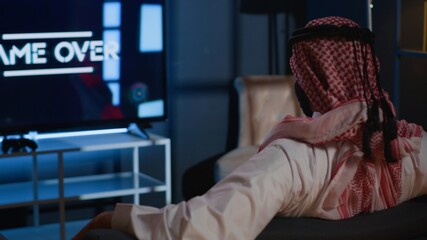 Middle Eastern man playing videogames on TV, relaxing after long day at work. Competitive gamer...