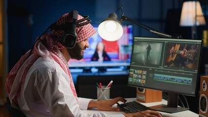 Muslim cinematographer wearing headphones while editing project, creating film montage, working...
