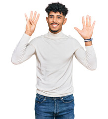Young arab man wearing casual winter sweater showing and pointing up with fingers number nine while smiling confident and happy.