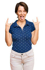 Young brunette woman with short hair wearing casual clothes shouting with crazy expression doing rock symbol with hands up. music star. heavy concept.