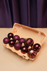 Cardboard egg tray with burgundy baubles. Creative new year's still life