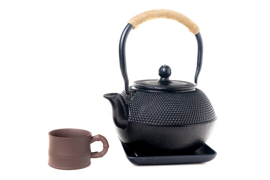 Traditional cast iron Asian teapot with clay cup on white background