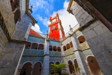Interior courtyard with the bright red main clock tower in view inside Pena Palace, in the mountains of Sintra, near Lisbon Portugal. - obrazy, fototapety, plakaty