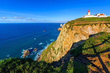 Fototapeta na wymiar The historic lighthouse at Cabo da Roca or Cape Roca, an Atlantic ocean cape at the westernmost point of the Sintra Mountain Range and continental Europe near Lisbon, Portugal.