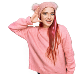 Young caucasian woman wearing casual clothes and wool cap smiling with hand over ear listening an hearing to rumor or gossip. deafness concept.
