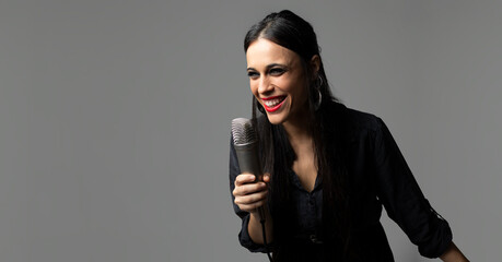 A young woman, rock singer, sings with a microphone in her hand while smiling