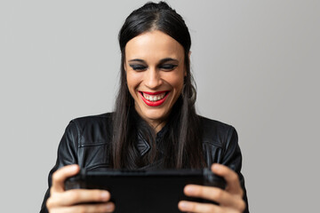 A young woman, with red lipstick, laughs happily as she plays with a handheld video game console...
