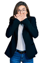 Young caucasian girl wearing business style and glasses shocked covering mouth with hands for mistake. secret concept.