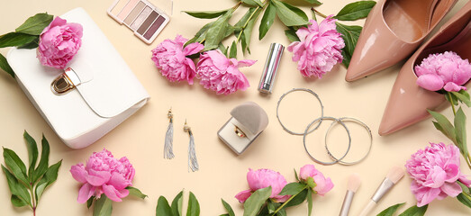 Composition with beautiful engagement ring, stylish accessories, makeup cosmetics and peony flowers on beige background