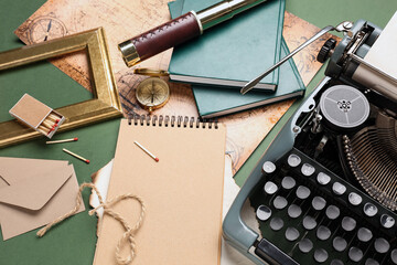 Composition with vintage typewriter, matches, notebook and books on green background