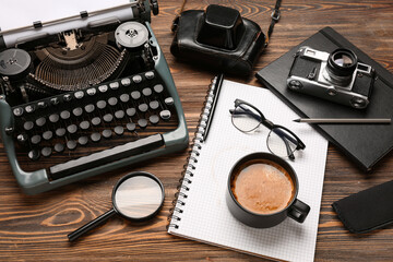 Composition with vintage typewriter, notebook, cup of coffee, glasses and magnifier on wooden table