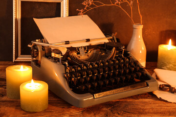 Vintage typewriter and burning candles  on wooden table