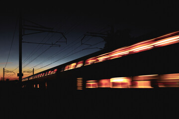 Vorbeifahrender Zug leuchtet in der Nacht bei Sonnenuntergang