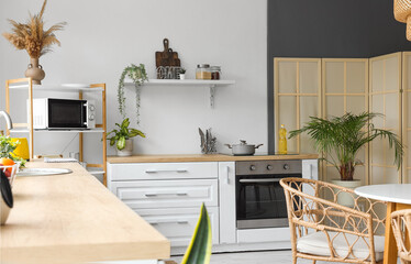 Interior of modern kitchen with white counters and microwave oven on shelving unit