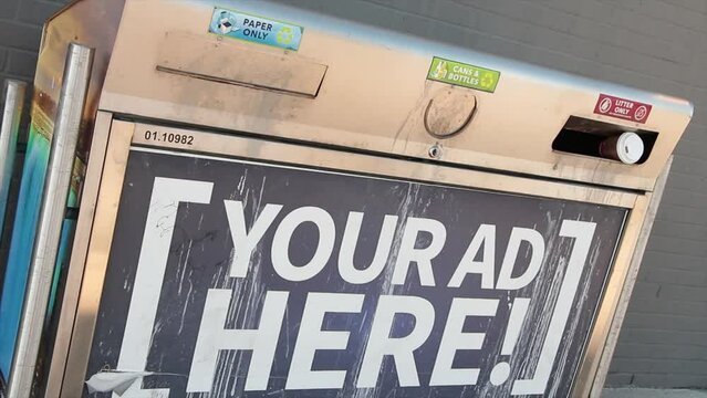 your ad here advertisement horizontal rectangle sign on public outdoor metal garbage bin with reflection of vehicle passing by