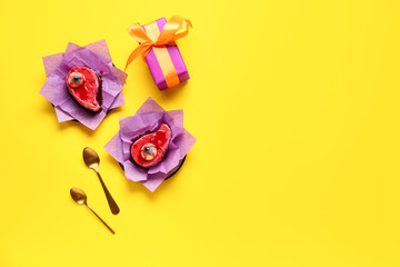 Delicious fruit cakes, gift box and spoons for Halloween celebration on yellow background