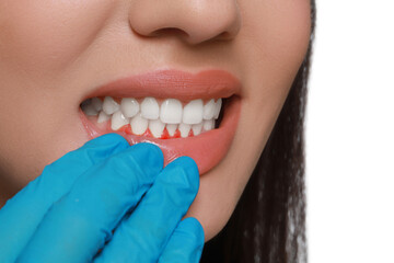 Doctor examining woman's inflamed gum on white background, closeup