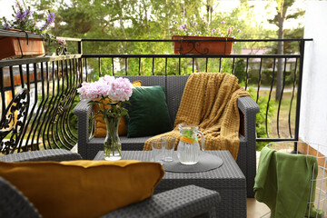 Rattan table with jug of water, glasses and beautiful flowers on terrace