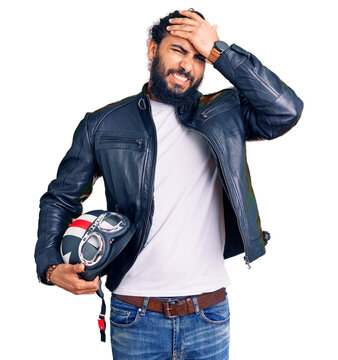 Young arab man holding motorcycle helmet stressed and frustrated with hand on head, surprised and angry face