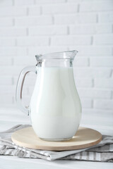 Jug of fresh milk on white wooden table