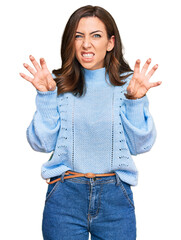 Young brunette woman wearing casual winter sweater smiling funny doing claw gesture as cat, aggressive and sexy expression