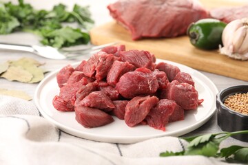 Plate with pieces of raw beef meat on table