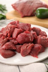 Plate with pieces of raw beef meat on table, closeup